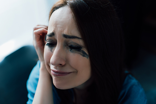 depressed woman with flowed mascara crying at home