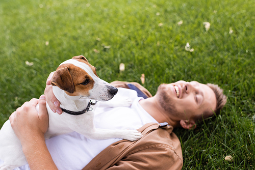 high angle view of man with jack russell terrier dog lying on green lawn with closed eyes