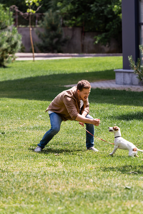 Selective focus of excited man feeding jack russell terrier in park