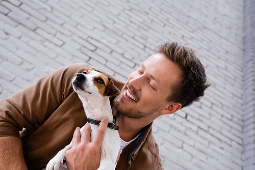Low angle view of young man embracing jack russell terrier near building