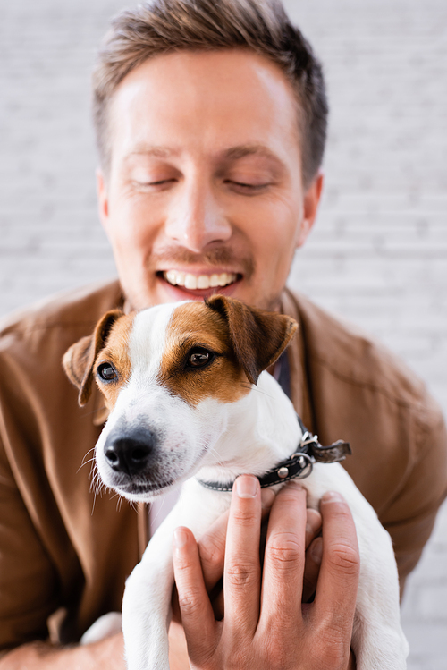 Selective focus of man hugging jack russell terrier  near building