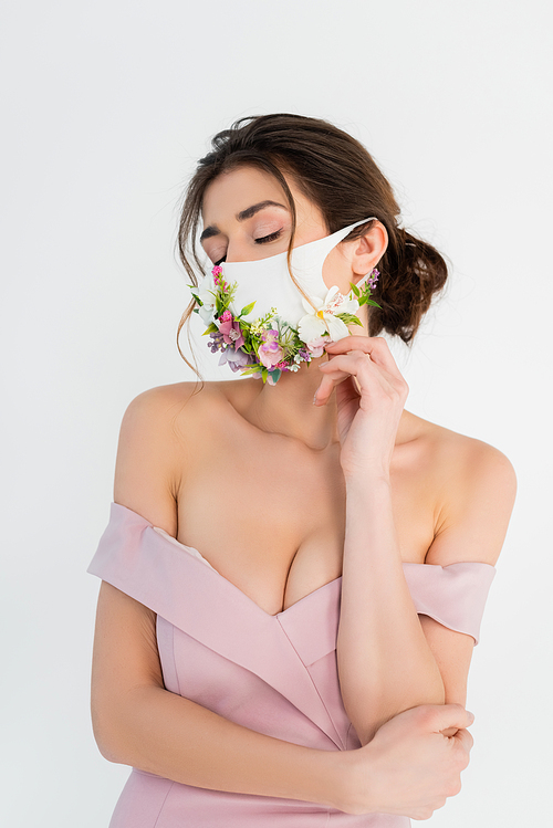 woman in pink dress and medical mask with flowers posing isolated on grey