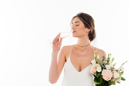 young fiancee holding wedding bouquet while drinking champagne isolated on white