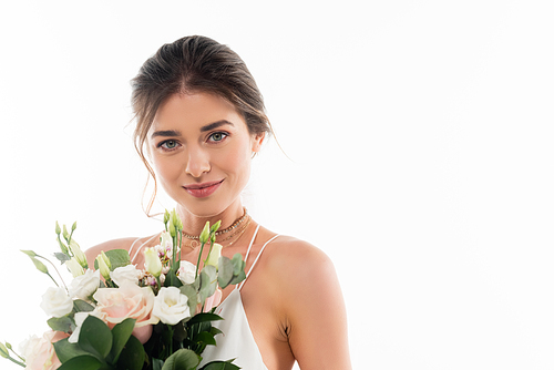 happy fiancee smiling at camera while holding wedding bouquet isolated on white