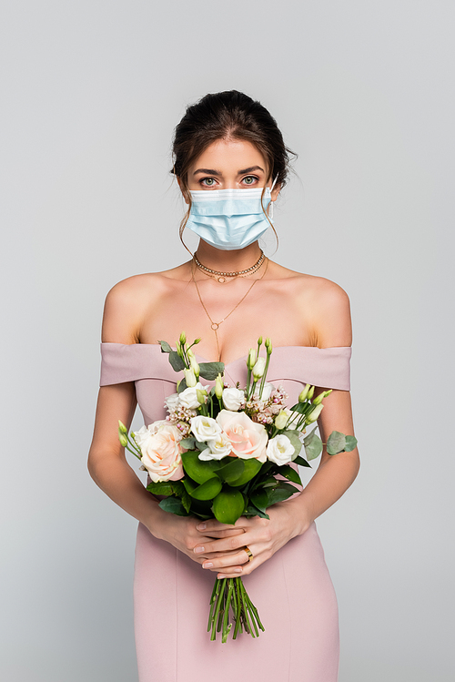 young fiancee in medical mask holding wedding bouquet isolated on grey
