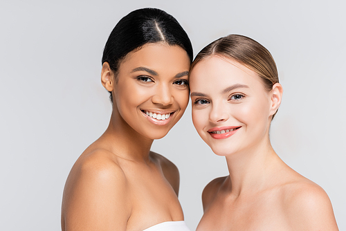 positive interracial women smiling while  isolated on grey