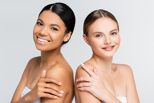 happy interracial women smiling while  isolated on grey