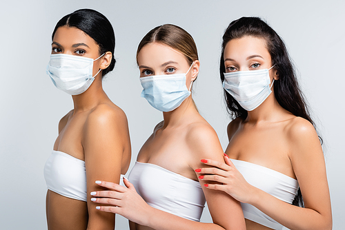 interracial women in tops with bare shoulders and medical masks isolated on grey