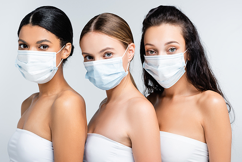 young interracial women in tops with bare shoulders and medical masks isolated on grey