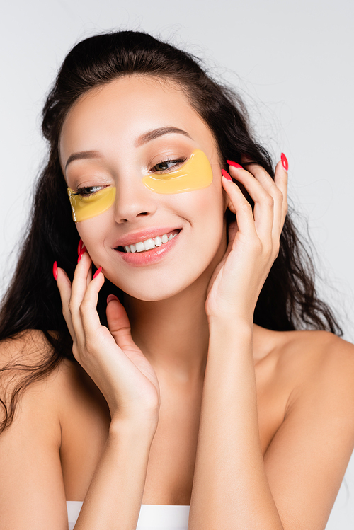 brunette woman with eye patches smiling and looking away isolated on white