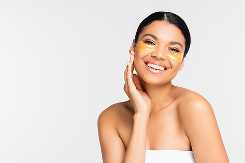 positive african american woman in golden eye patches smiling isolated on white