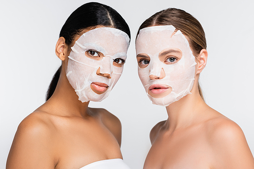multiethnic women in moisturizing sheet masks isolated on white
