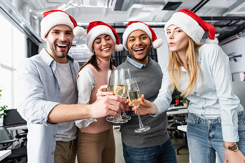 Multiethnic businesspeople smiling while clinking with champagne during new year in office
