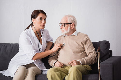 social worker checking health of aged patient with stethoscope