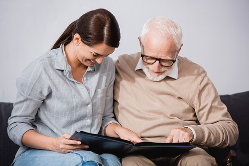 brunette woman with elderly father looking at photo album together