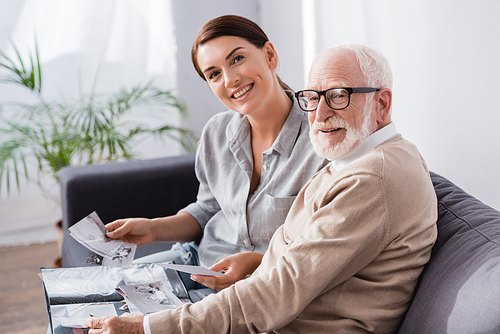 smiling woman with elderly father  while looking at family photos together