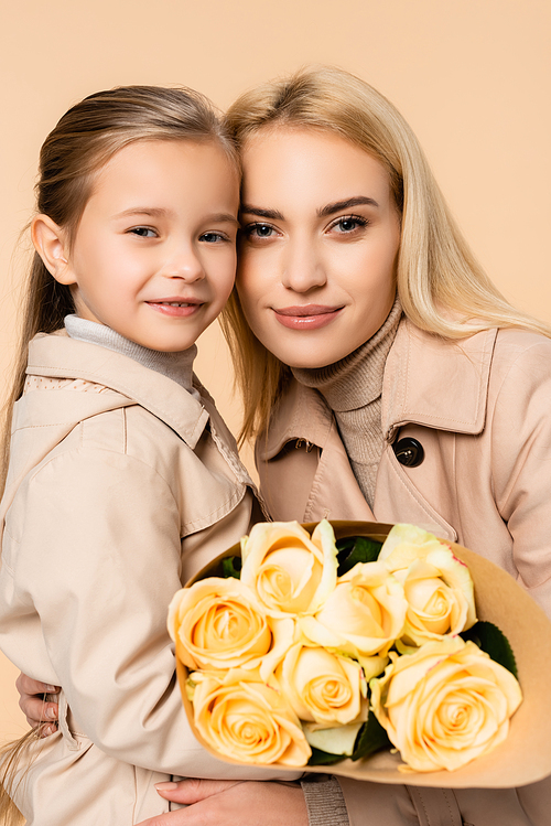 joyful kid holding roses near cheerful mother on 8 march isolated on beige