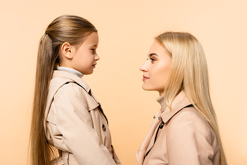 side view of mother and daughter looking at each other isolated on beige