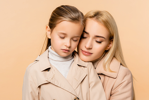 caring mother and daughter with closed eyes embracing isolated on beige