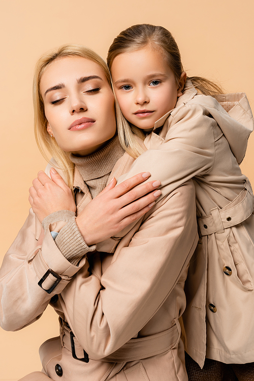 daughter hugging caring mother with closed eyes isolated on beige