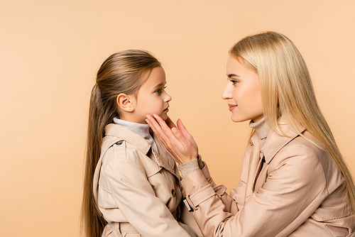 side view of caring mother touching face of daughter isolated on beige