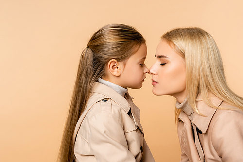 side view of mother and kid touching noses isolated on beige