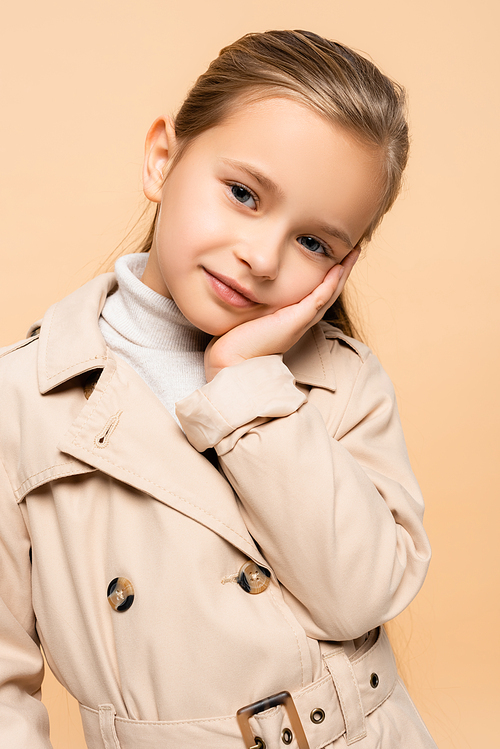 pleased child in trench coat  isolated on beige