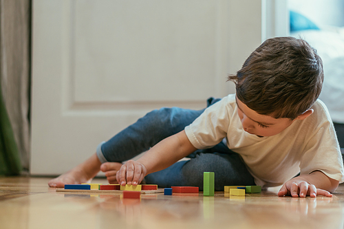 selective focus of cute toddler kid playing with toys on floor