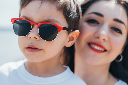 selective focus of stylish boy in sunglasses near happy mother
