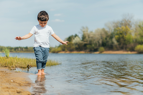 selective focus of cute boy standing in pond