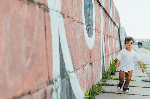 selective focus of cute boy running near wall with graffiti