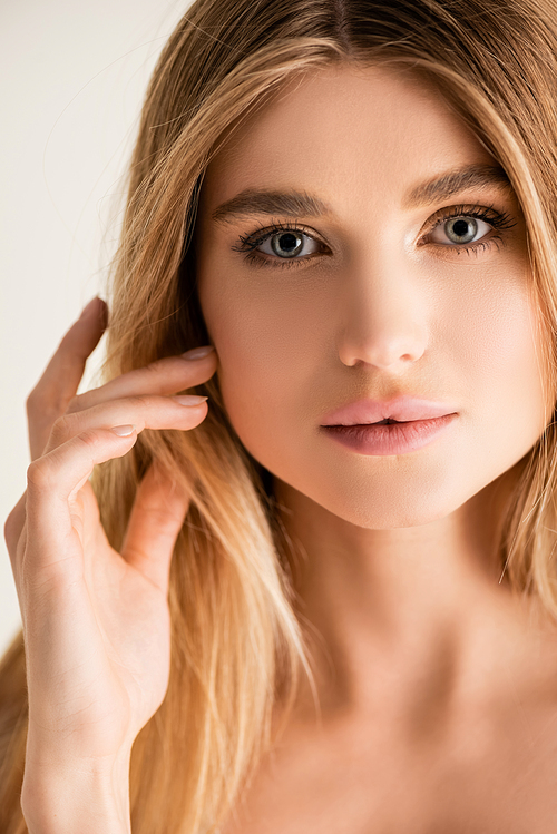 young blonde model  while fixing hair isolated on white