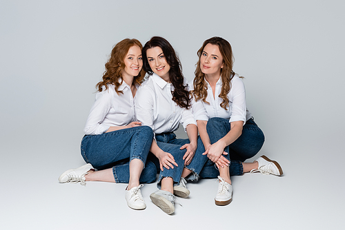 Adult friends in white shirts sitting on grey background