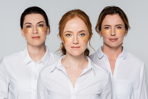 Red haired woman with eye patches  near friends blurred isolated on grey