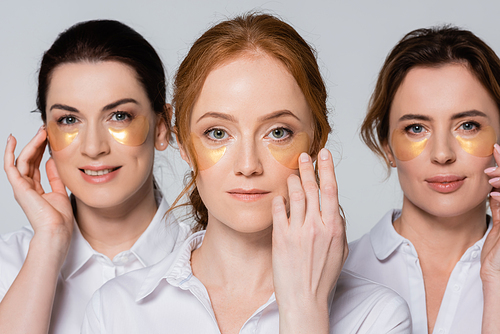 Red haired woman with eye patches  near friends isolated on grey