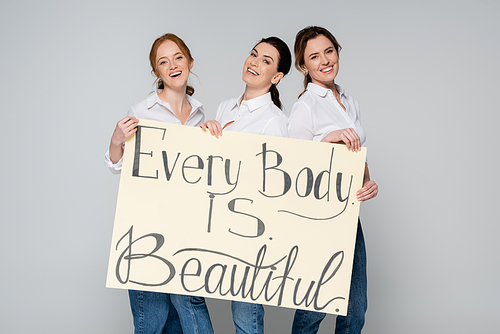 Adult women holding placard with every body is beautiful lettering isolated on grey