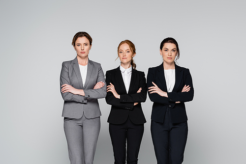 Adult managers standing with crossed arms isolated on grey