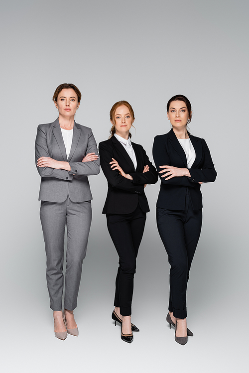 Businesswomen in formal wear posing on grey background