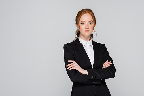 Red haired businesswoman standing with crossed arms isolated on grey