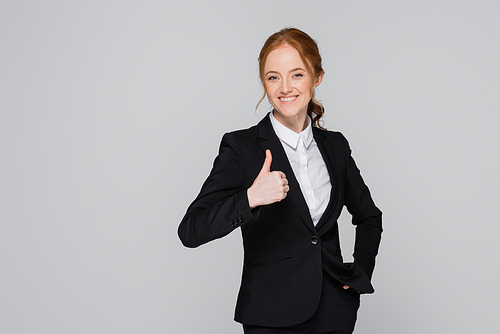 Smiling businesswoman showing approved gesture isolated on grey