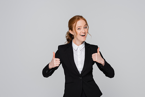 Happy businesswoman showing thumbs up isolated on grey