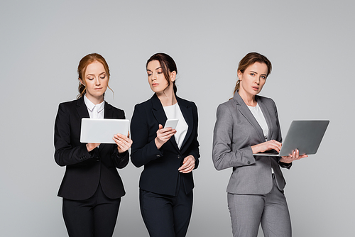 Businesswomen using devices isolated on grey