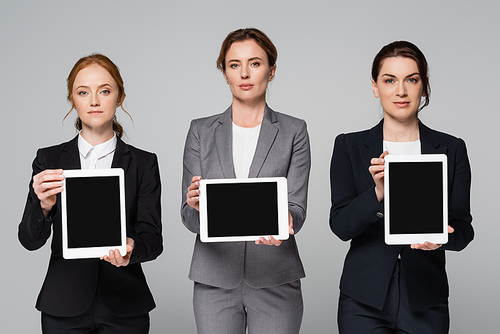 Businesswomen holding digital tablets with blank screen isolated on grey