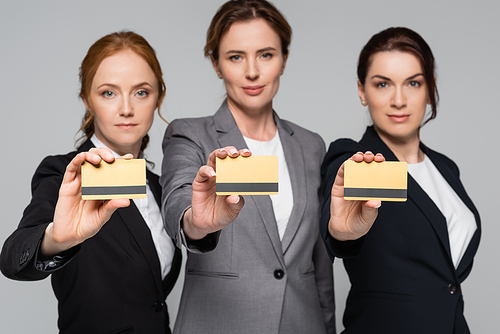 Credit cards in hands of businesswomen on blurred background isolated on grey