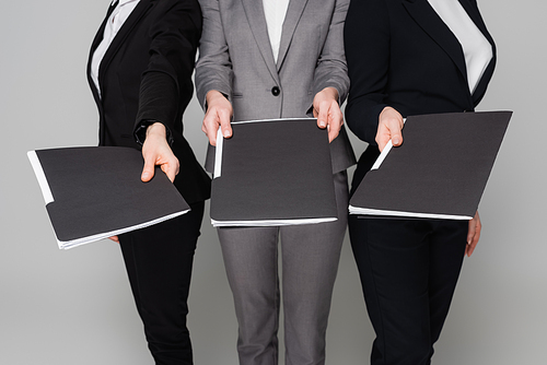 Cropped view of businesswomen holding paper folders isolated on grey