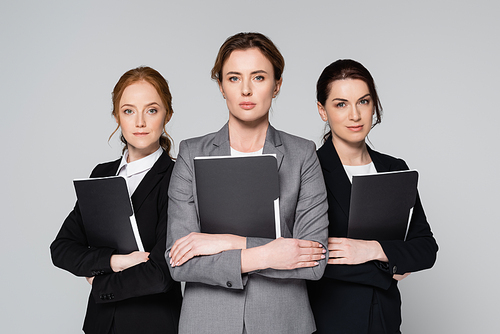 Businesswomen in formal wear holding paper folders isolated on grey