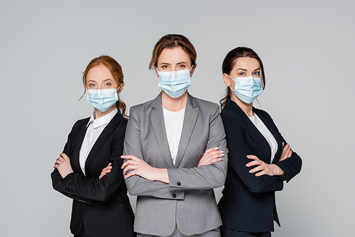 Businesswomen in suits and medical masks  isolated on grey