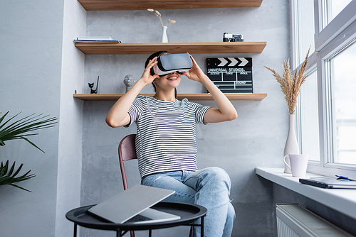 Selective focus of freelancer using vr headset near laptop on coffee table at home