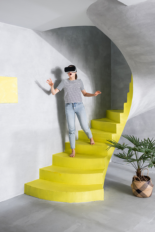 Excited woman using virtual reality headset on stairs home