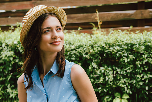 happy young woman in straw hat looking away outside